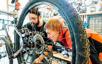 Student learning how to fix a bike at the Spoke bike shop